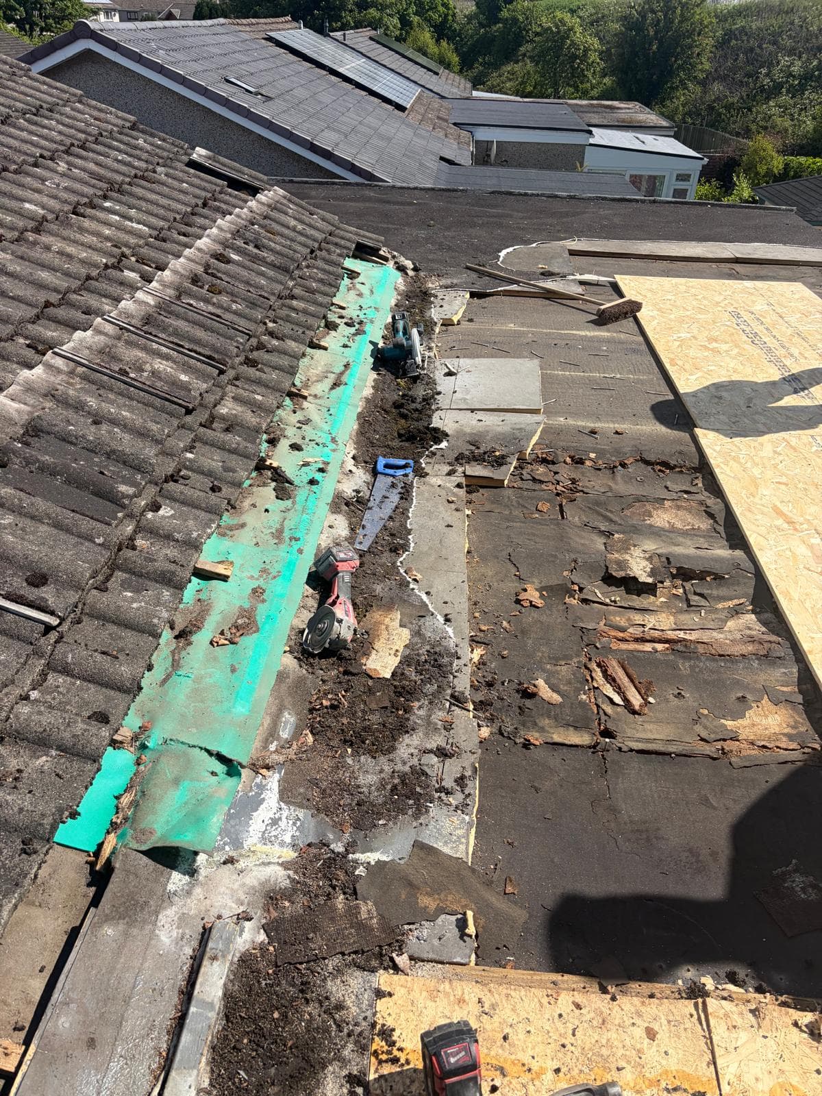 Flat roof opened during repairs with damaged decking and replacement boards visible